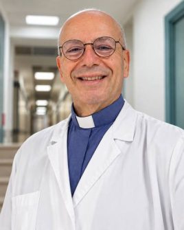 Don Romano De Angelis, cappellano dell'Ospedale pediatrico Bambino Gesù, in camice bianco in una corsia